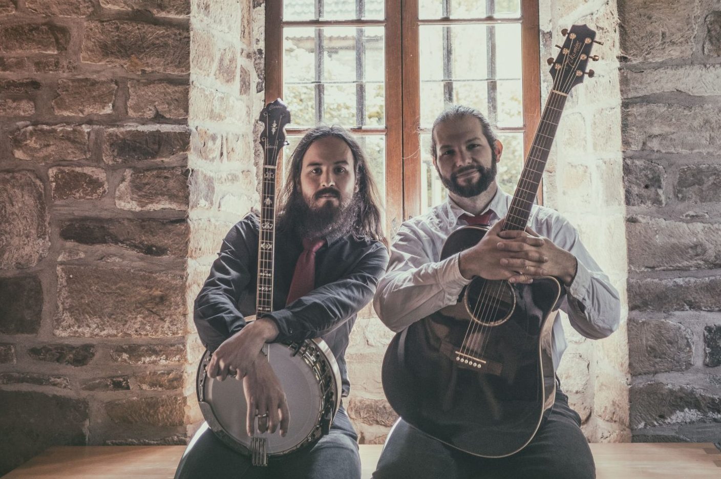 "Undaunted" von STOUT will irischen Folk neu interpretieren Duo STOUT steht mit Banjo und Gitarre vor einem Gewölbefenster